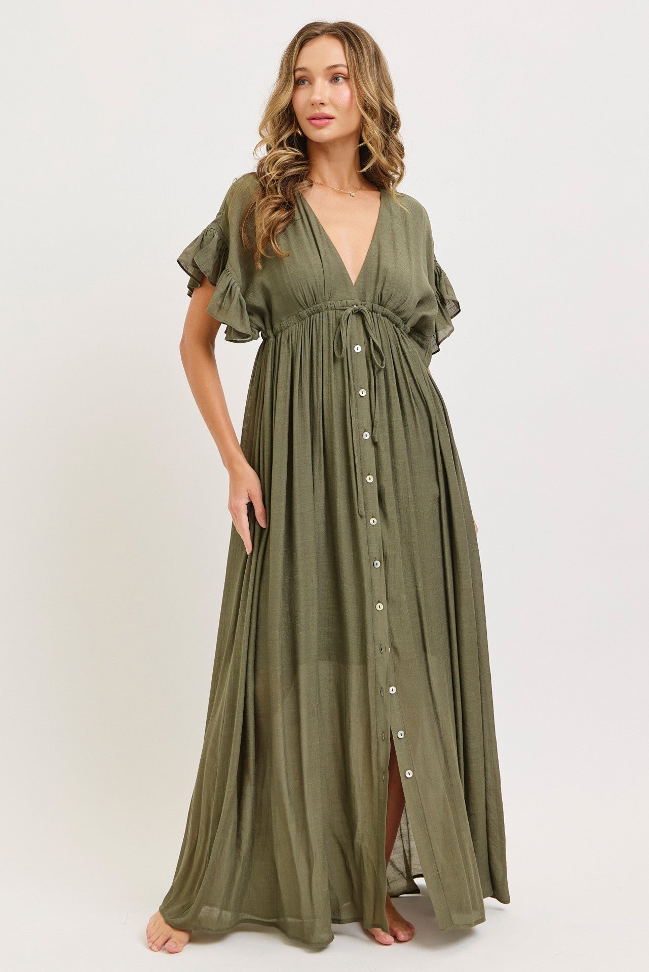 woman wearing an olive green maxi dress with a deep V-neck, ruffled sleeves, and button details.