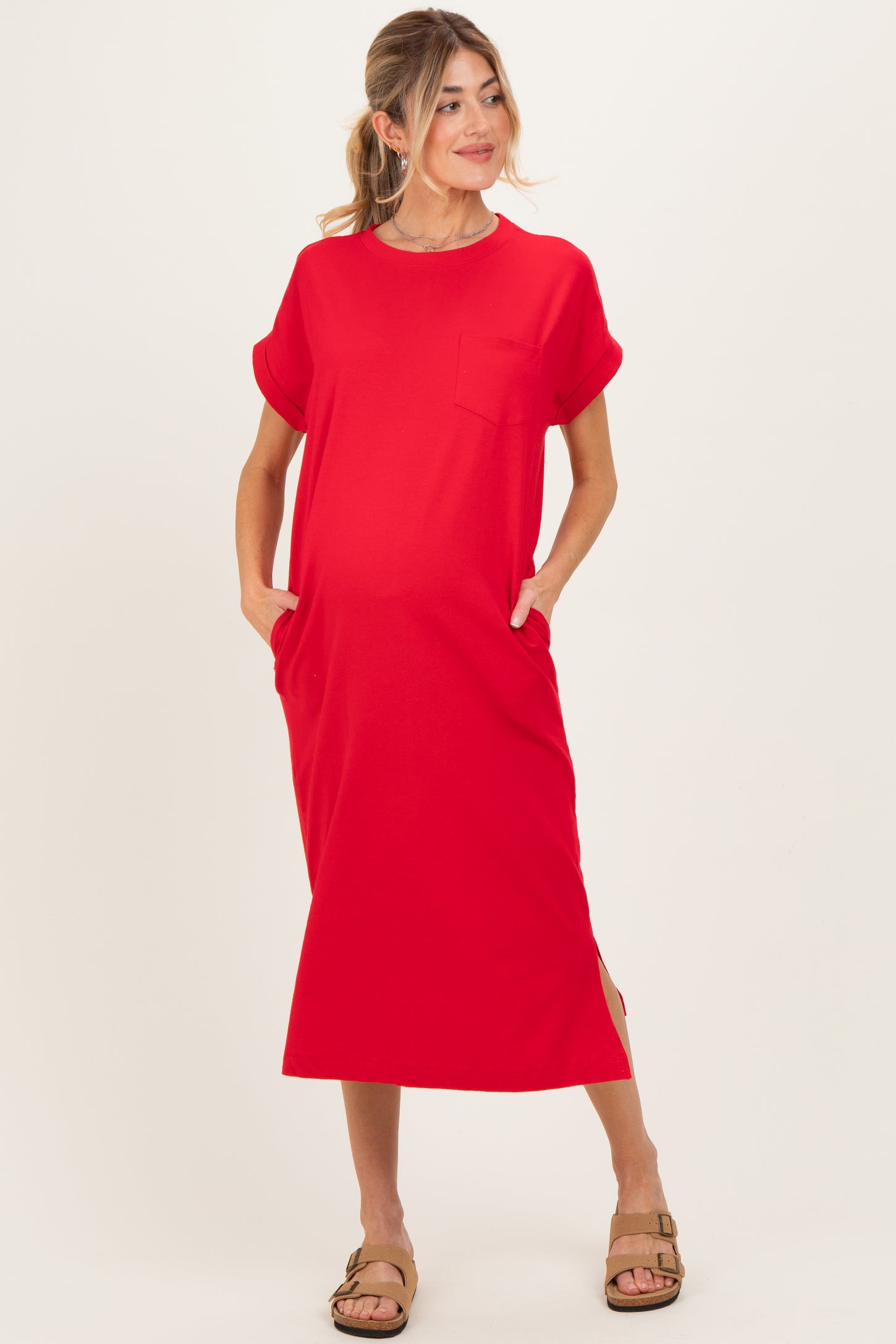 woman wearing a red short sleeve maternity dress with pockets and side slits, showing her baby bump