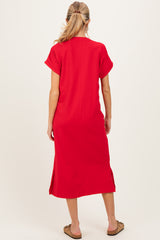 woman wearing a red maternity maxi dress with short sleeves and side slits, standing with her back to the camera