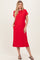 woman wearing a red short sleeve midi dress with a pocket and side slits, standing with one hand in the pocket
