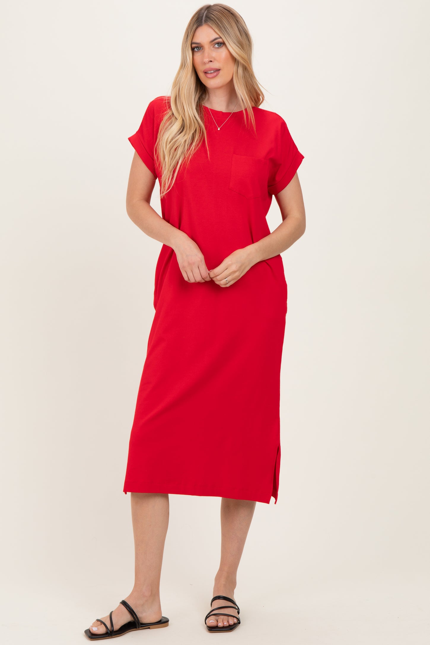 woman wearing a red short sleeve midi dress with a pocket and side slits, standing and smiling in black sandals