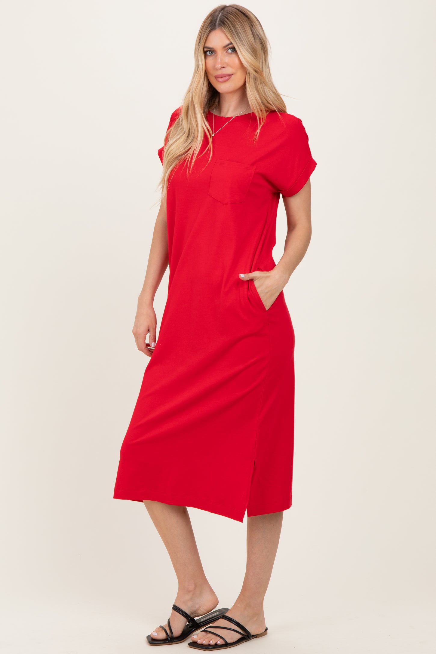 woman wearing a red short sleeve midi dress with a pocket and side slit, standing with hands in pockets