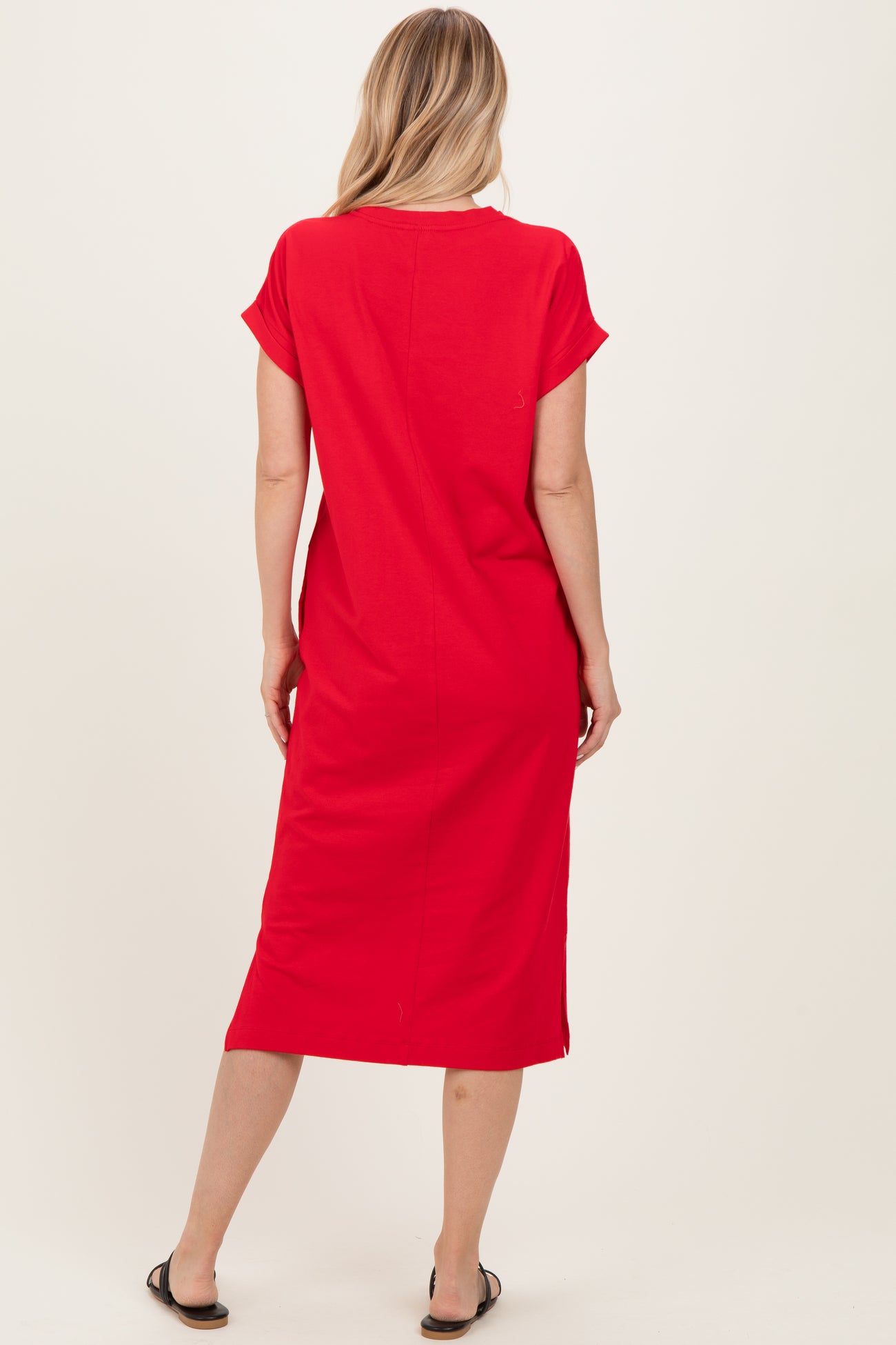 woman wearing a red short sleeve midi dress, showing the back view with a straight cut and side slits
