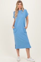 woman wearing a light blue short sleeve midi dress with side pockets and slits, standing on a neutral background