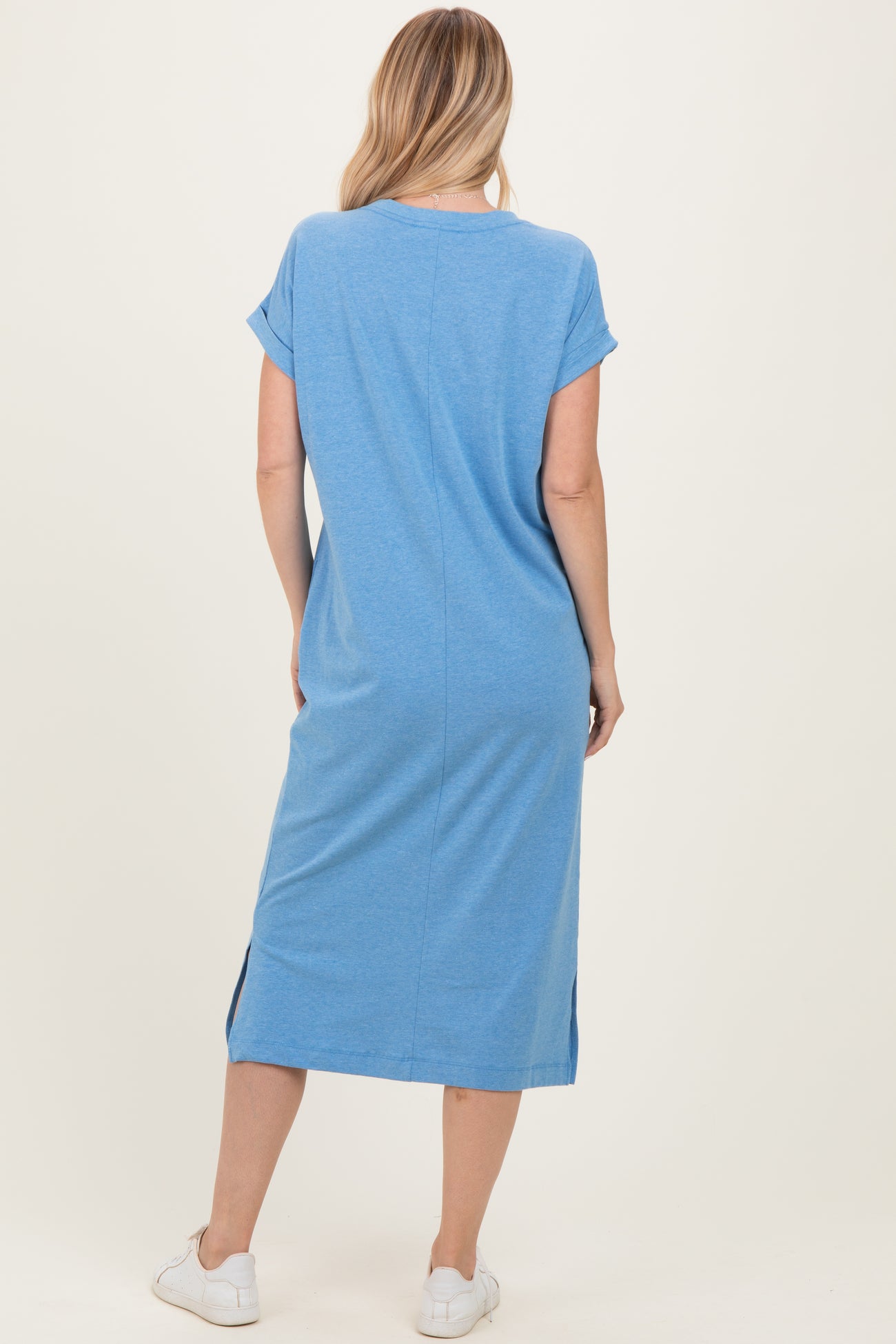 woman wearing a casual blue short sleeve midi dress with side slits and white sneakers