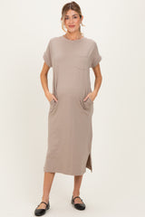 woman wearing a taupe short sleeve maternity dress with side pockets and a relaxed fit, showing her baby bump