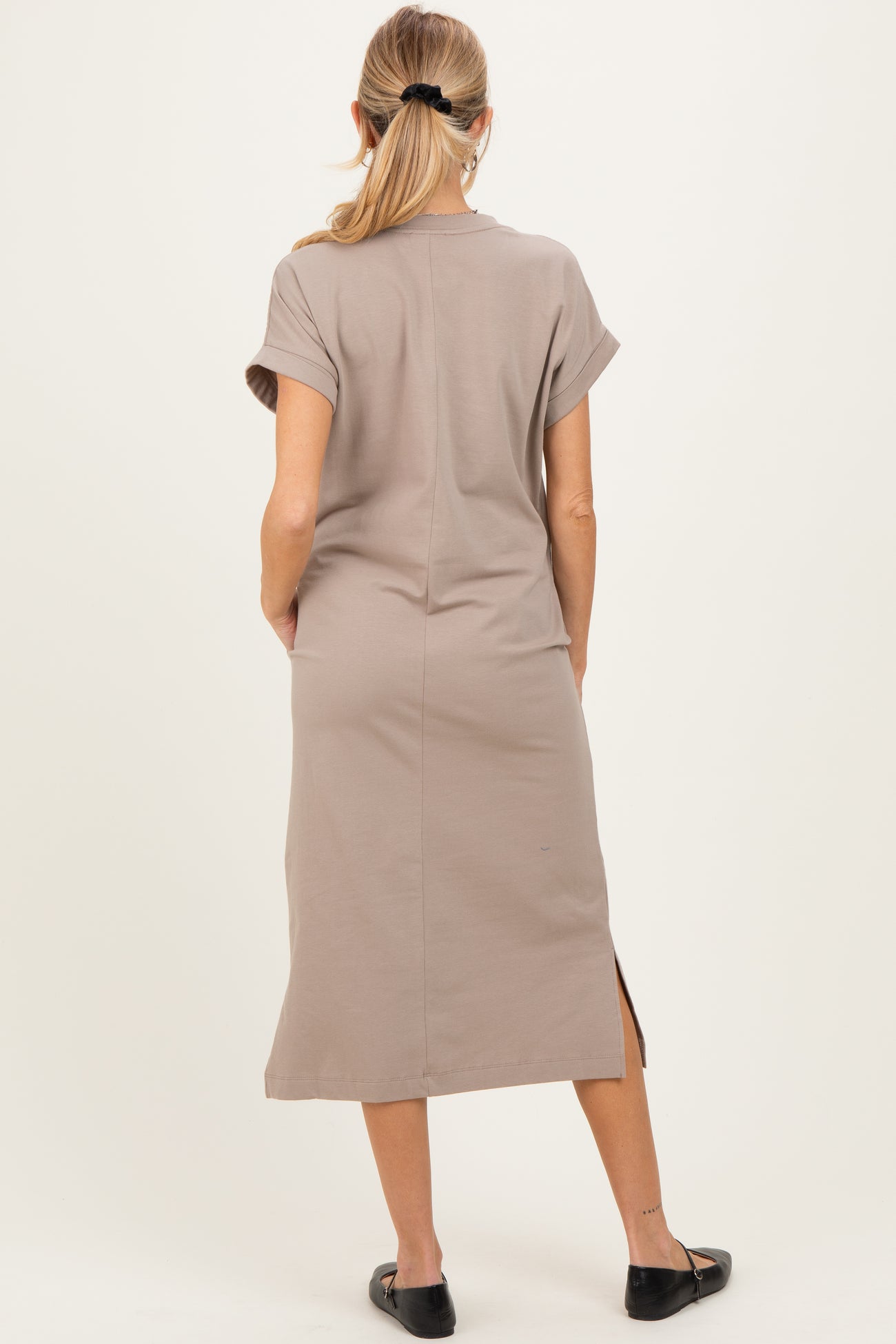 woman wearing a taupe maternity dress with short sleeves and a side slit, viewed from the back