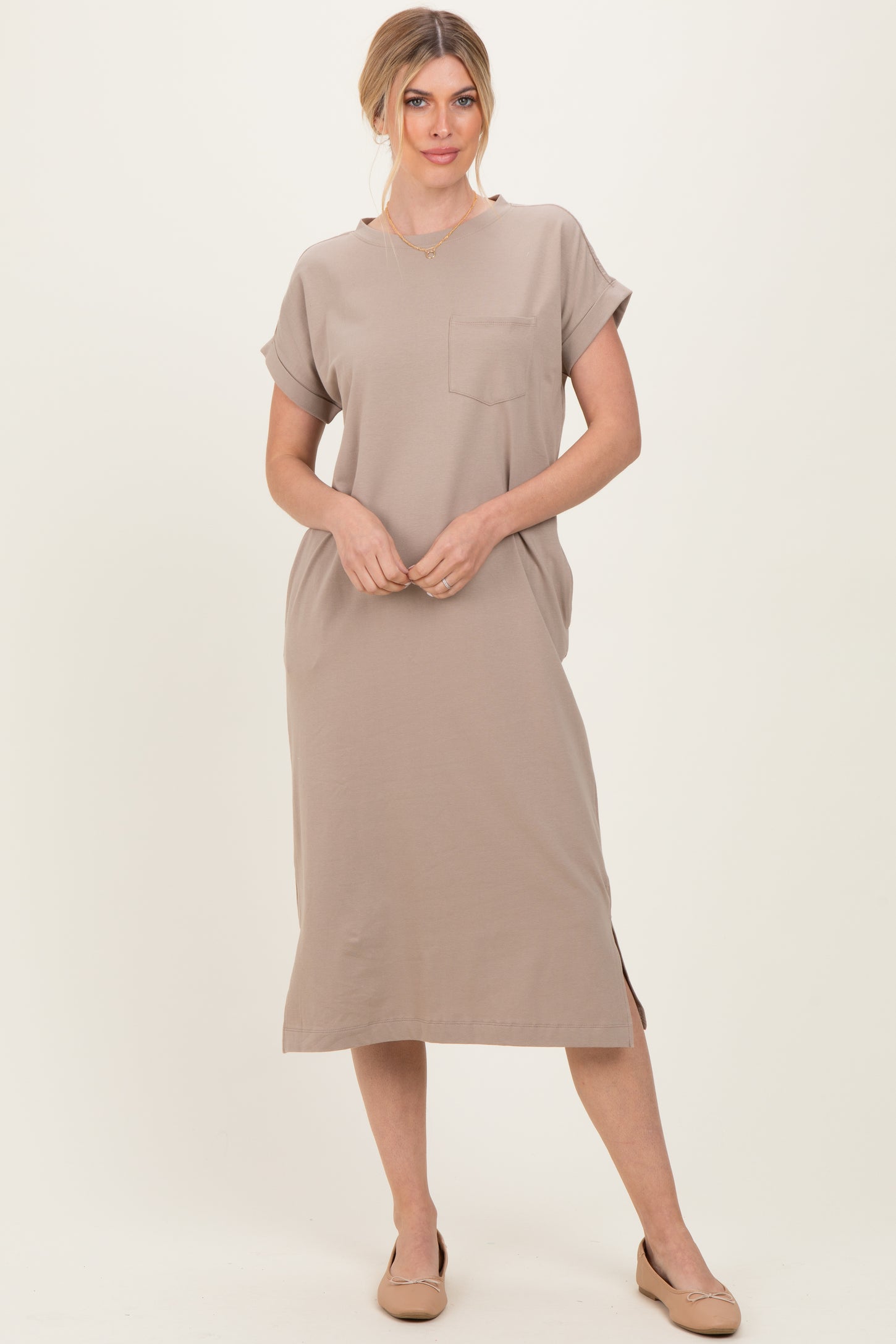 woman wearing a beige short sleeve midi dress with a pocket and side slit, styled with nude flats