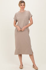 woman wearing a beige short sleeve midi dress with a pocket and side slit, styled with nude flats