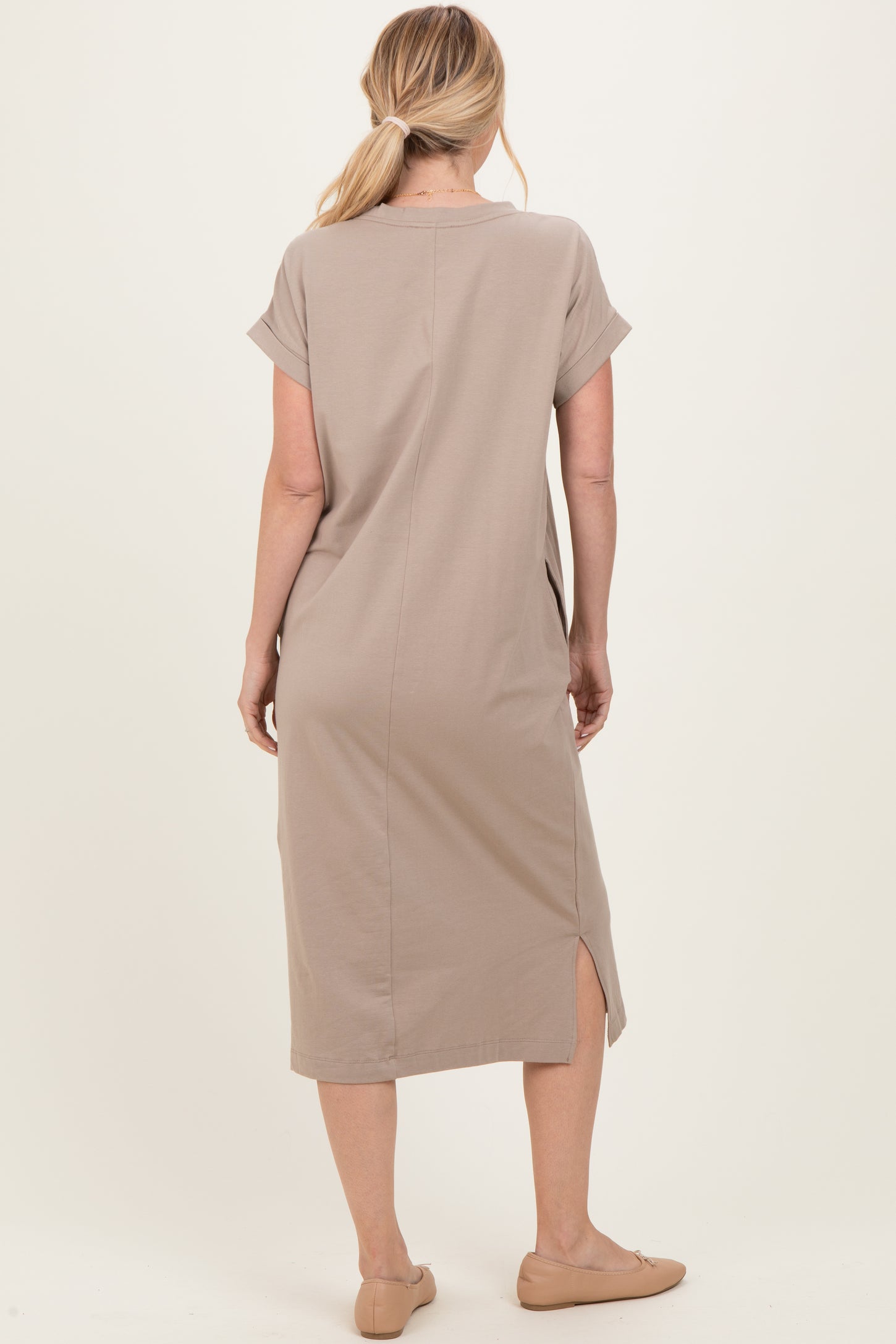woman wearing a taupe short sleeve midi dress with side slits and a relaxed fit, viewed from the back