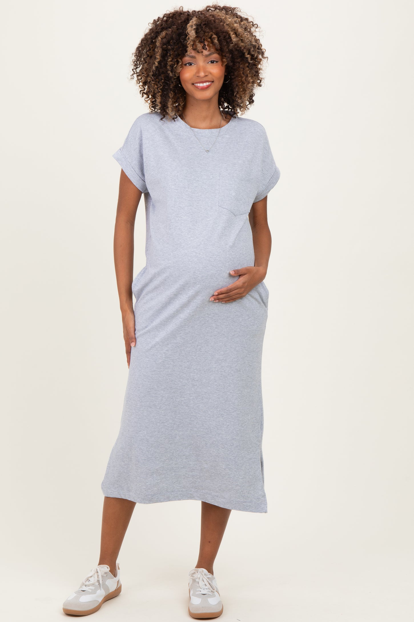 woman wearing a gray short sleeve maternity dress with a pocket and holding her baby bump