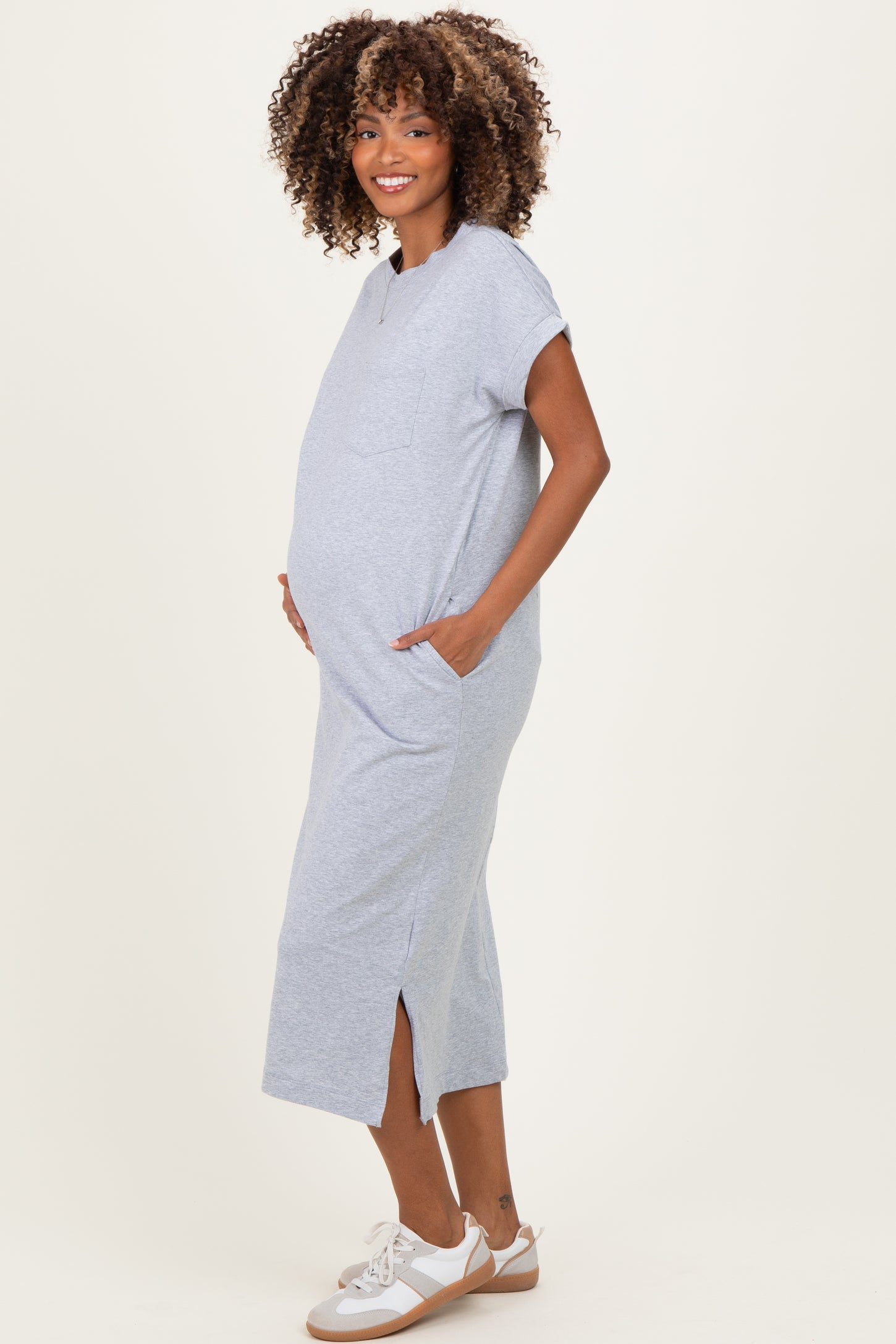 woman wearing a grey maternity maxi dress with short sleeves and side pockets, showcasing her baby bump