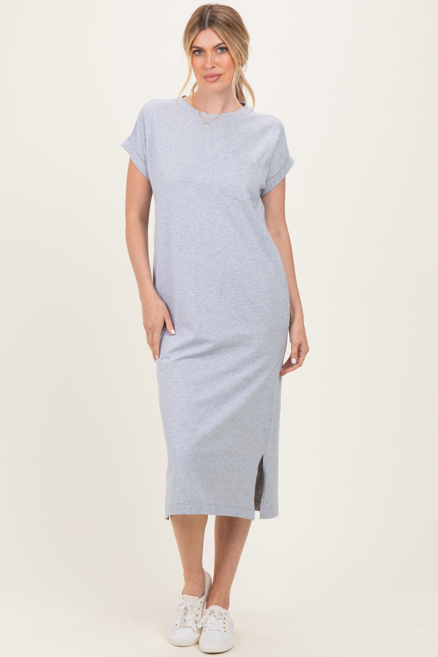 woman wearing a gray midi t-shirt dress with short sleeves and side slits, styled with white sneakers