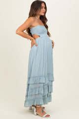 woman wearing a light blue maternity maxi dress with ruffled hem and cut-out sides, showing her baby bump