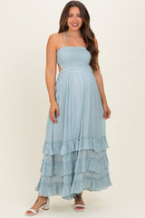 woman wearing a light blue maternity maxi dress with ruffle details and a smocked bodice, posing with a baby bump visible