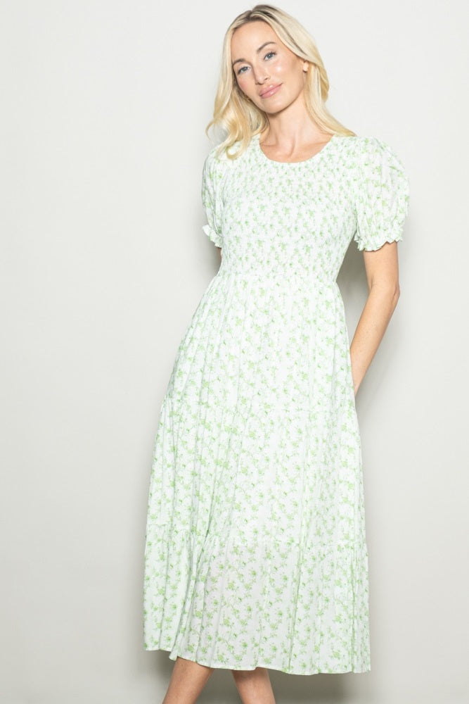 woman wearing a green floral midi dress with puff sleeves and a fitted bodice