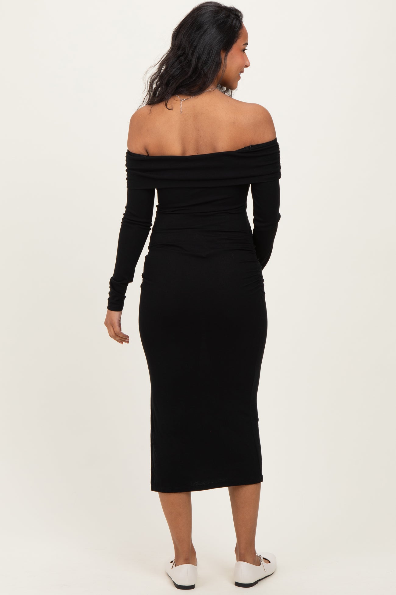 woman wearing a black off-the-shoulder maternity dress with long sleeves and a fitted silhouette