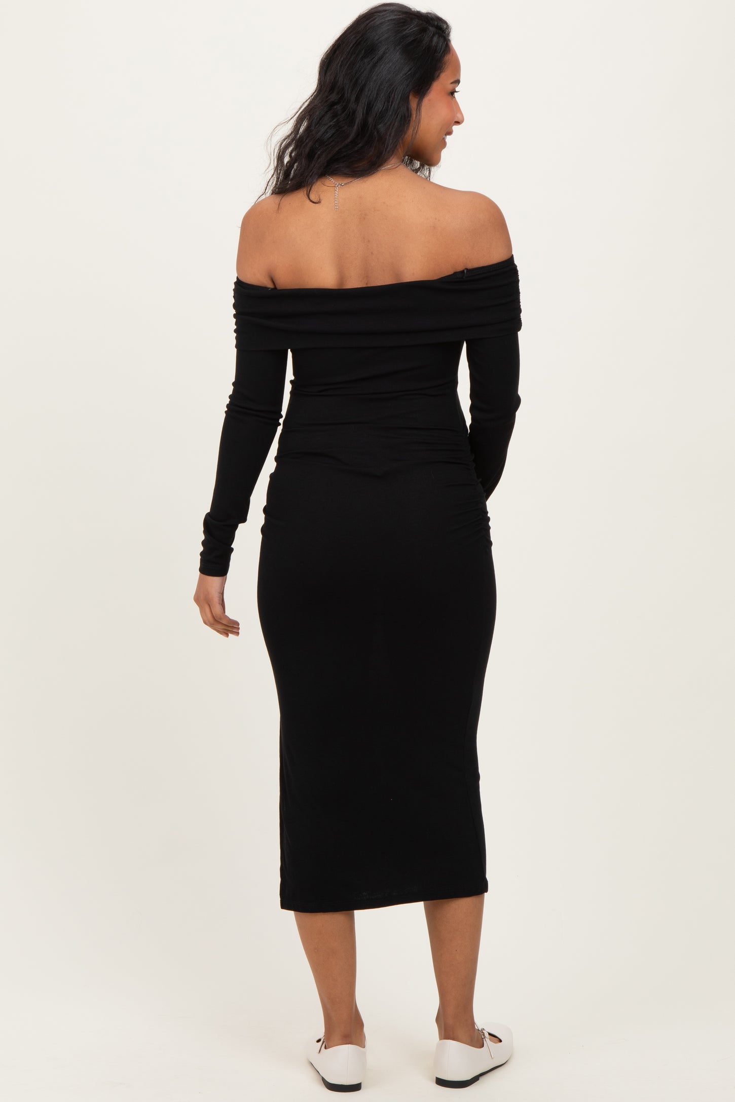 woman wearing a black off-the-shoulder maternity dress with long sleeves and a fitted silhouette