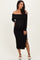 woman wearing a black off-shoulder maternity dress with side slit and holding her baby bump