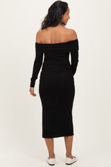 woman wearing a black off-the-shoulder maternity dress with long sleeves and a fitted silhouette