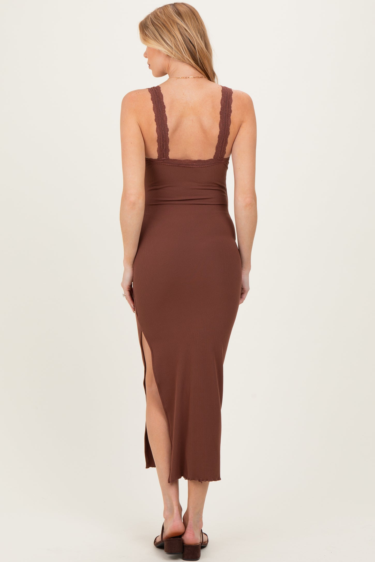 woman wearing a brown ribbed maternity dress with lace straps and a side slit, showing a pregnant belly