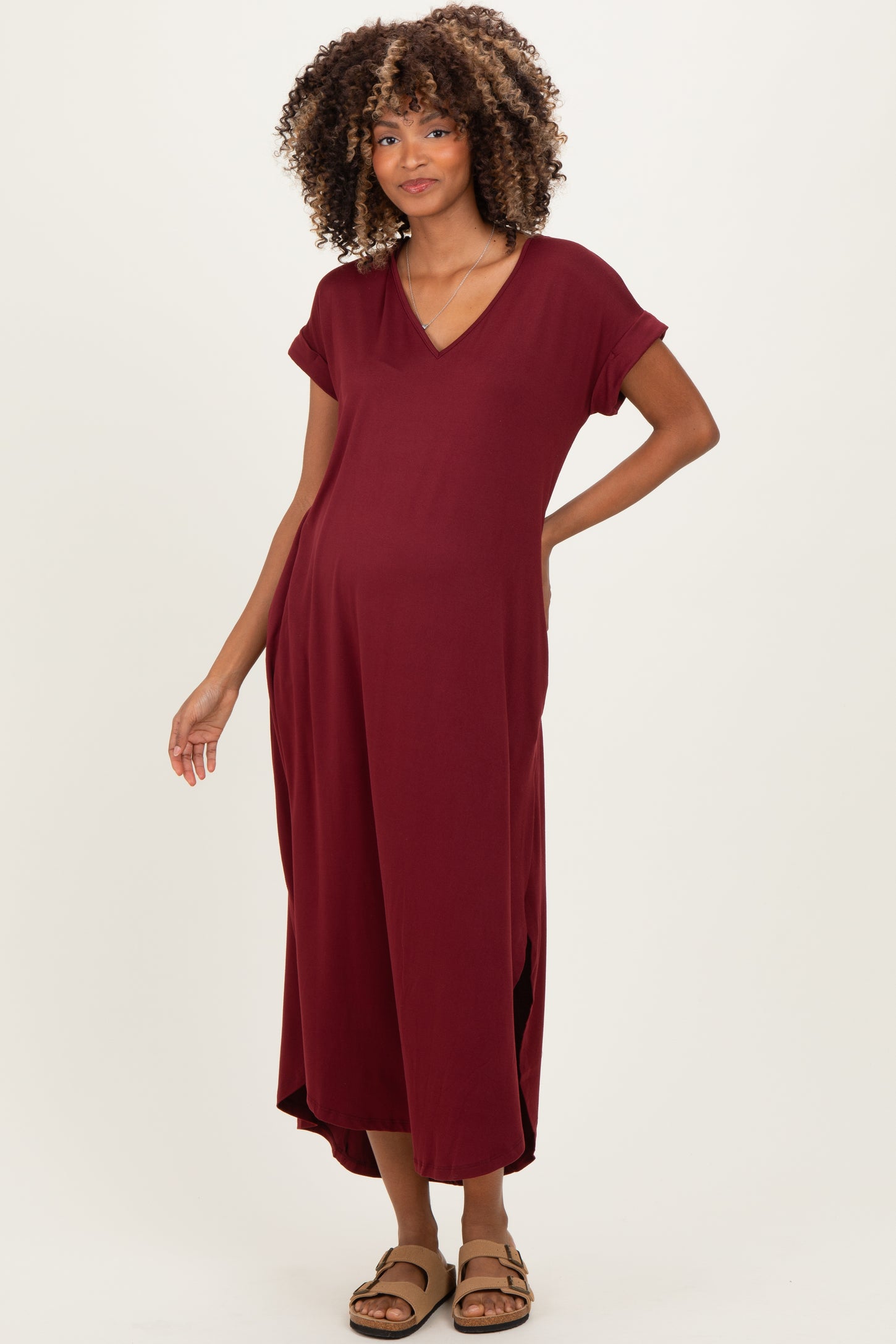woman wearing a burgundy maternity maxi dress with short sleeves and a v-neck, showing her baby bump