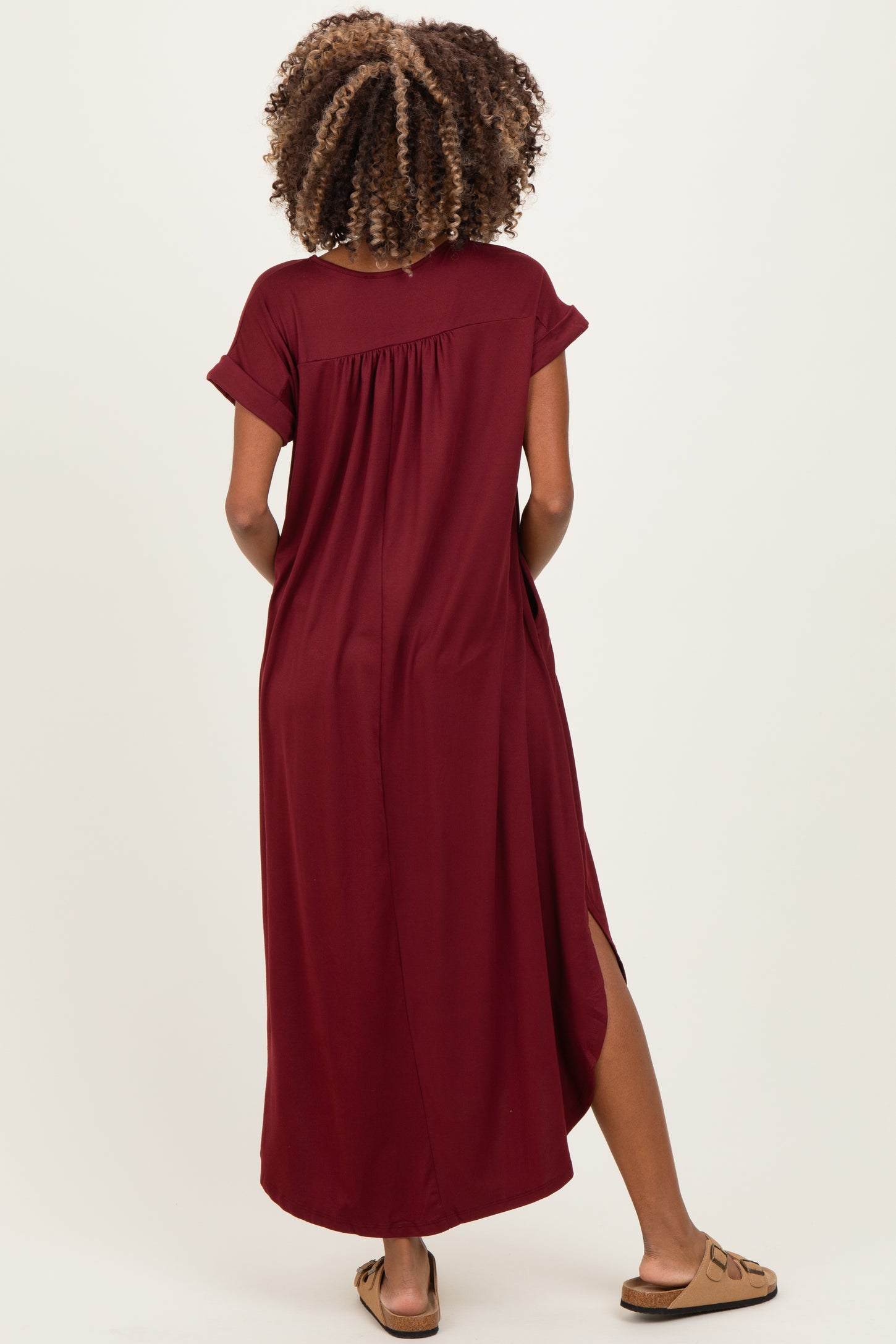 woman wearing a burgundy short sleeve maternity maxi dress with side slits and visible baby bump