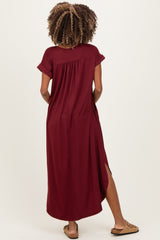 woman wearing a burgundy short sleeve maternity maxi dress with side slits and visible baby bump