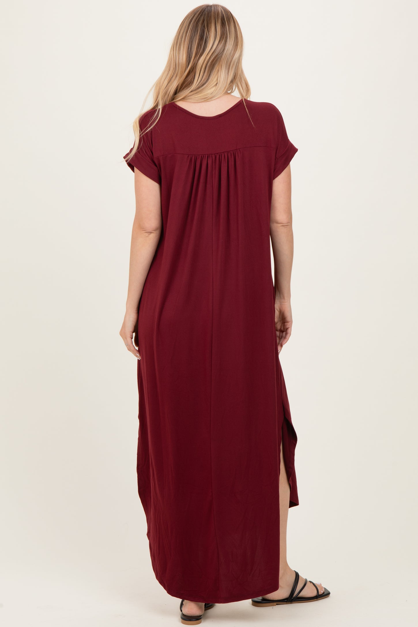 woman wearing a burgundy maxi dress with short sleeves and side slits, shown from the back