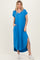 woman wearing a bright blue short sleeve maxi dress with side pockets and side slits, poses with one hand in pocket