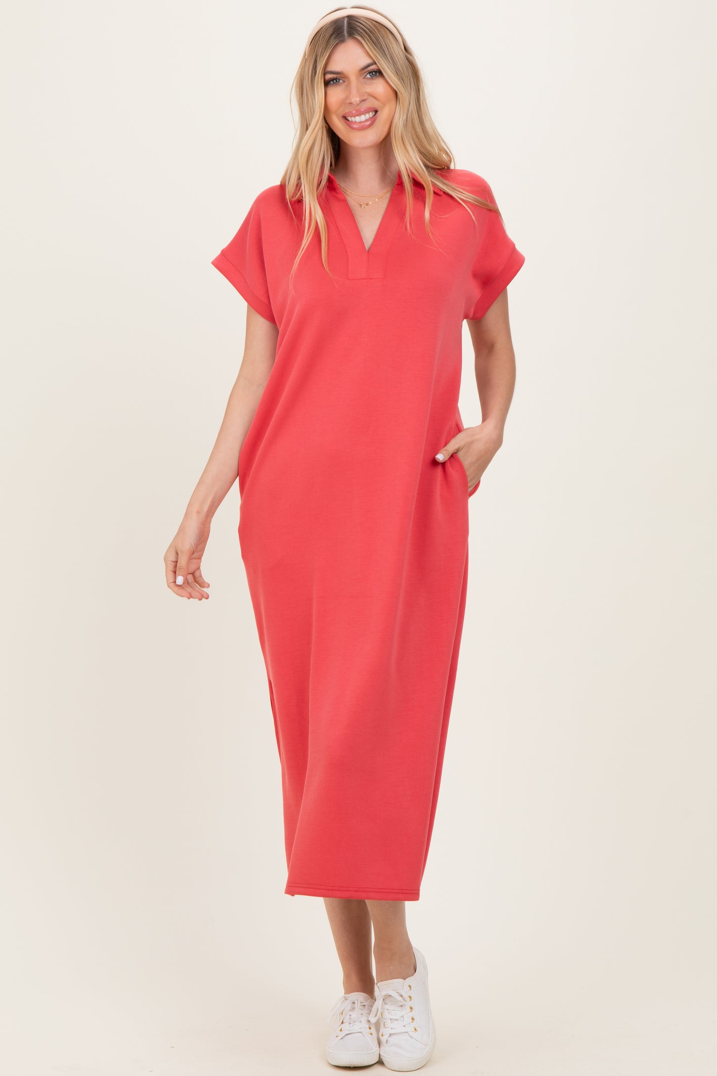 woman wearing a coral short sleeve maxi dress with a v-neck and pockets, standing and smiling