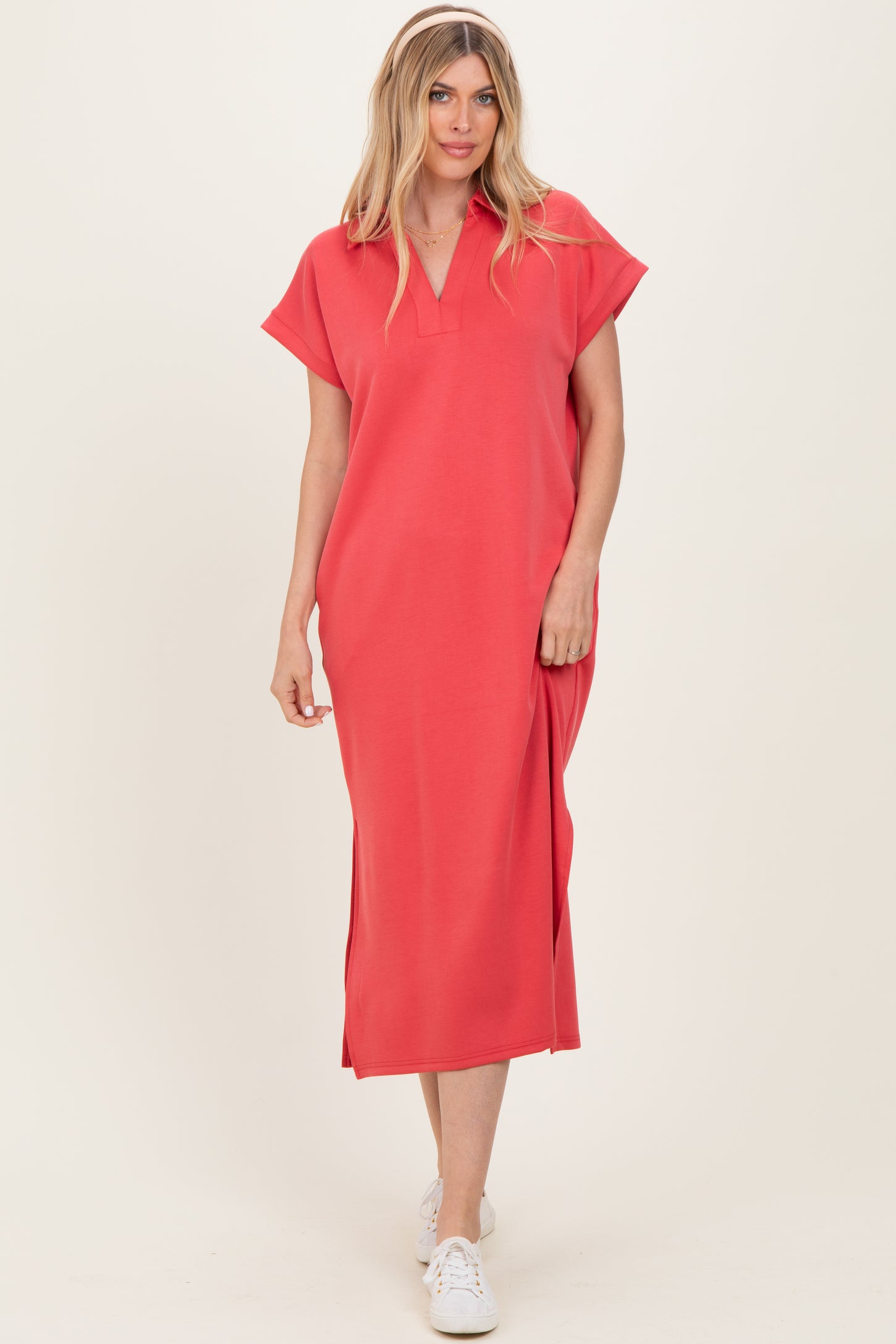 woman wearing a coral midi dress with cap sleeves and a v-neckline, styled with white sneakers