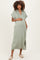 woman wearing a sage green maternity dress with short sleeves and side slits, holding her baby bump