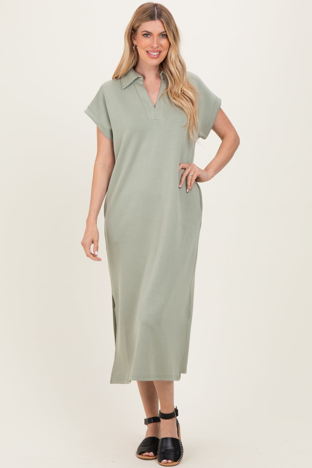 woman wearing a sage green collared maxi dress with short sleeves and side slits, standing and smiling