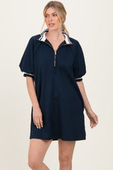 woman wearing a navy zip-up polo dress with short puff sleeves and white accents