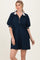 woman wearing a navy zip-up polo dress with short puff sleeves and white accents