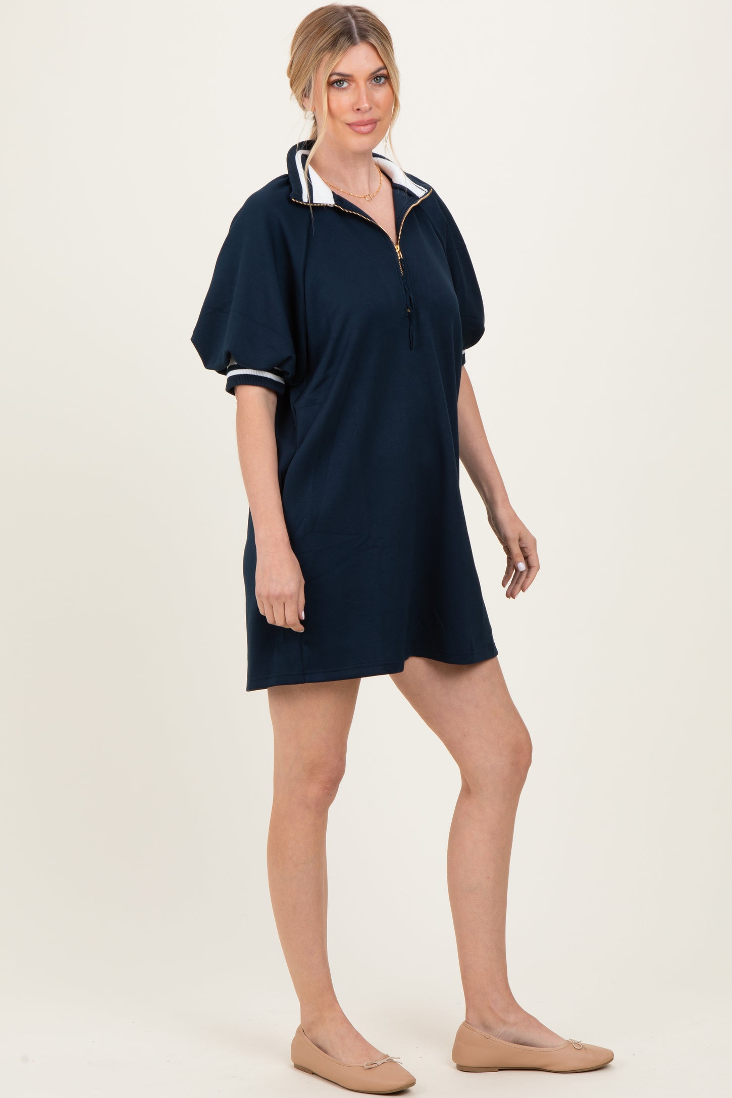 woman wearing a navy blue short sleeve pullover dress with a half zipper and contrasting collar