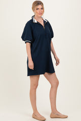 woman wearing a navy blue short sleeve pullover dress with a half zipper and contrasting collar