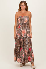 woman wearing a strapless maxi dress with a leopard print and floral design in brown and pink tones