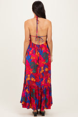 back view of a woman wearing a colorful floral maxi dress with a tie-back detail and ruffled hemline