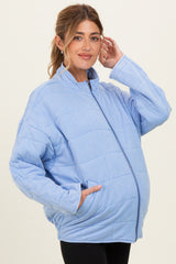 woman wearing a light blue quilted maternity jacket with a zipper and front pockets, showing her baby bump