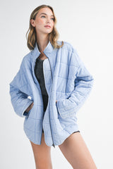 woman wearing a light blue quilted zip-up jacket with an oversized fit and gray top underneath