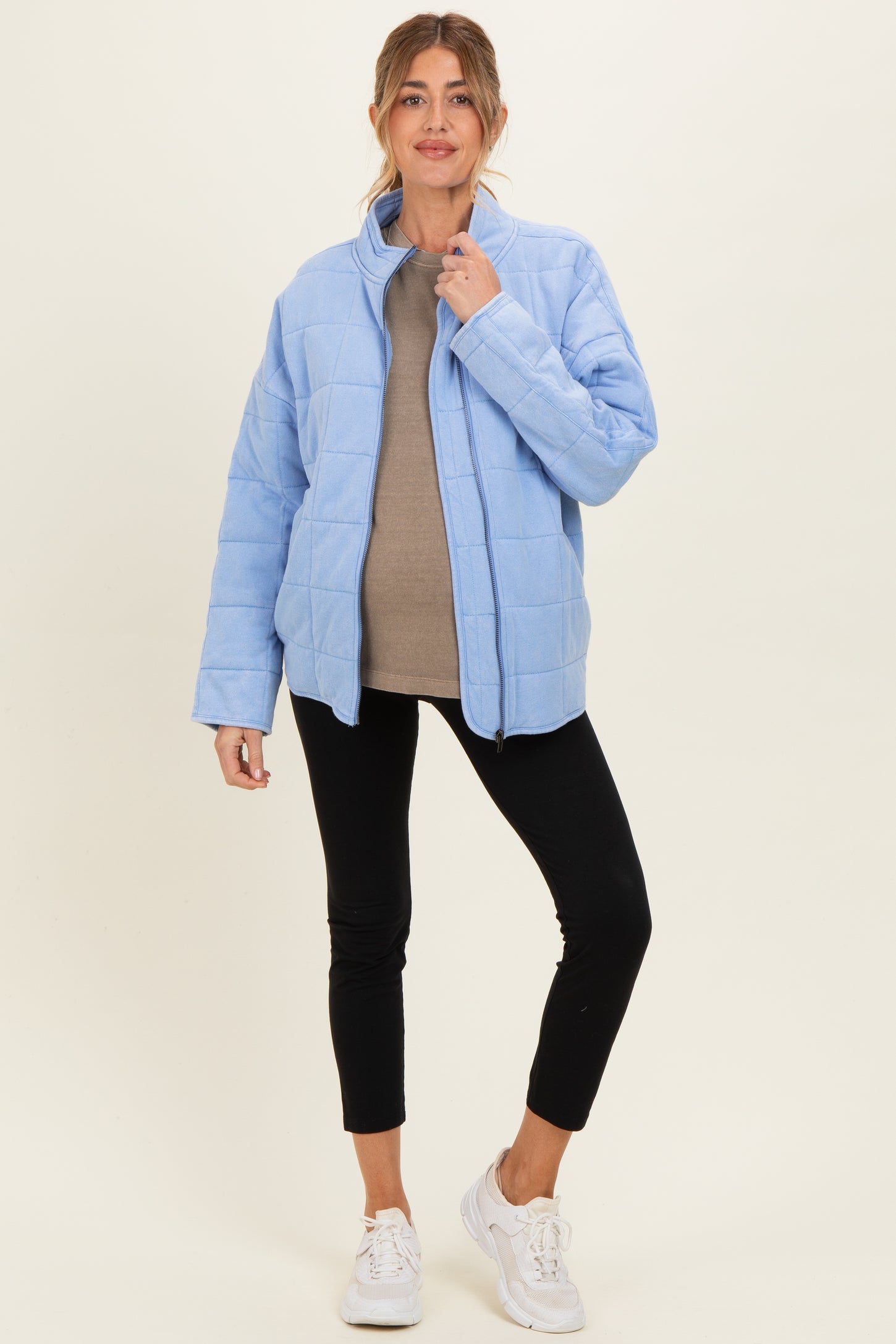 woman wearing a light blue quilted maternity jacket over a beige top and black leggings