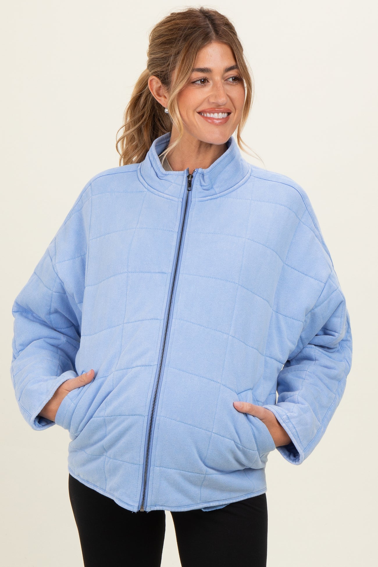 woman wearing a light blue quilted maternity jacket with side pockets and a high collar