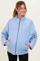 woman wearing a light blue quilted maternity jacket with side pockets and a high collar