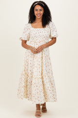 woman wearing a cream floral print maxi dress with puff sleeves and a tiered skirt