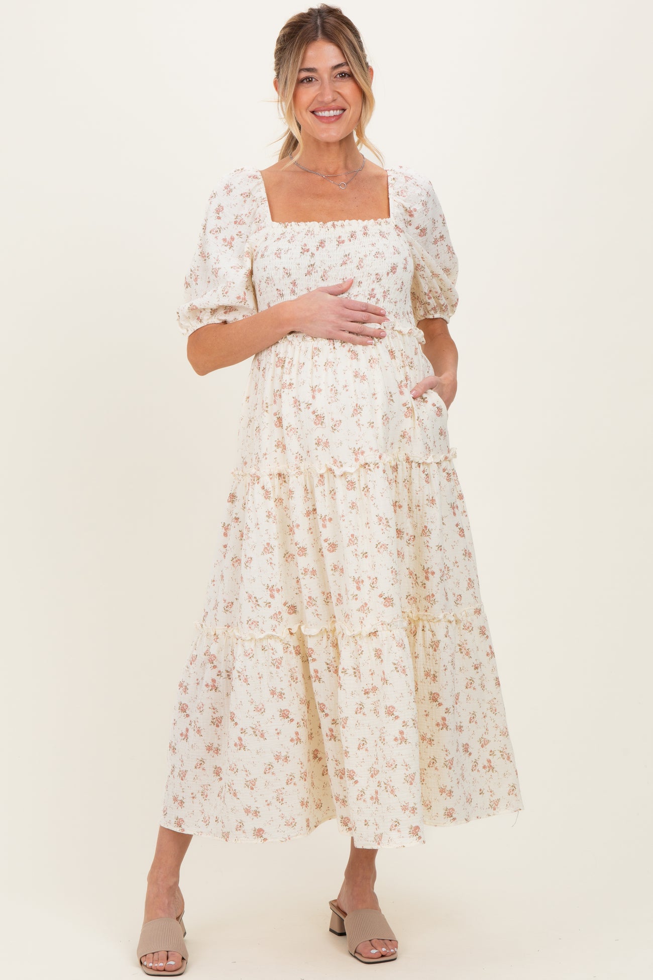 woman wearing a floral print maternity maxi dress with a square neckline and puff sleeves, showing her baby bump