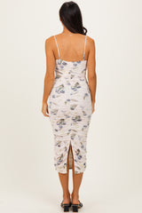 woman wearing a fitted floral midi dress with ruching and a back slit, showing the back view