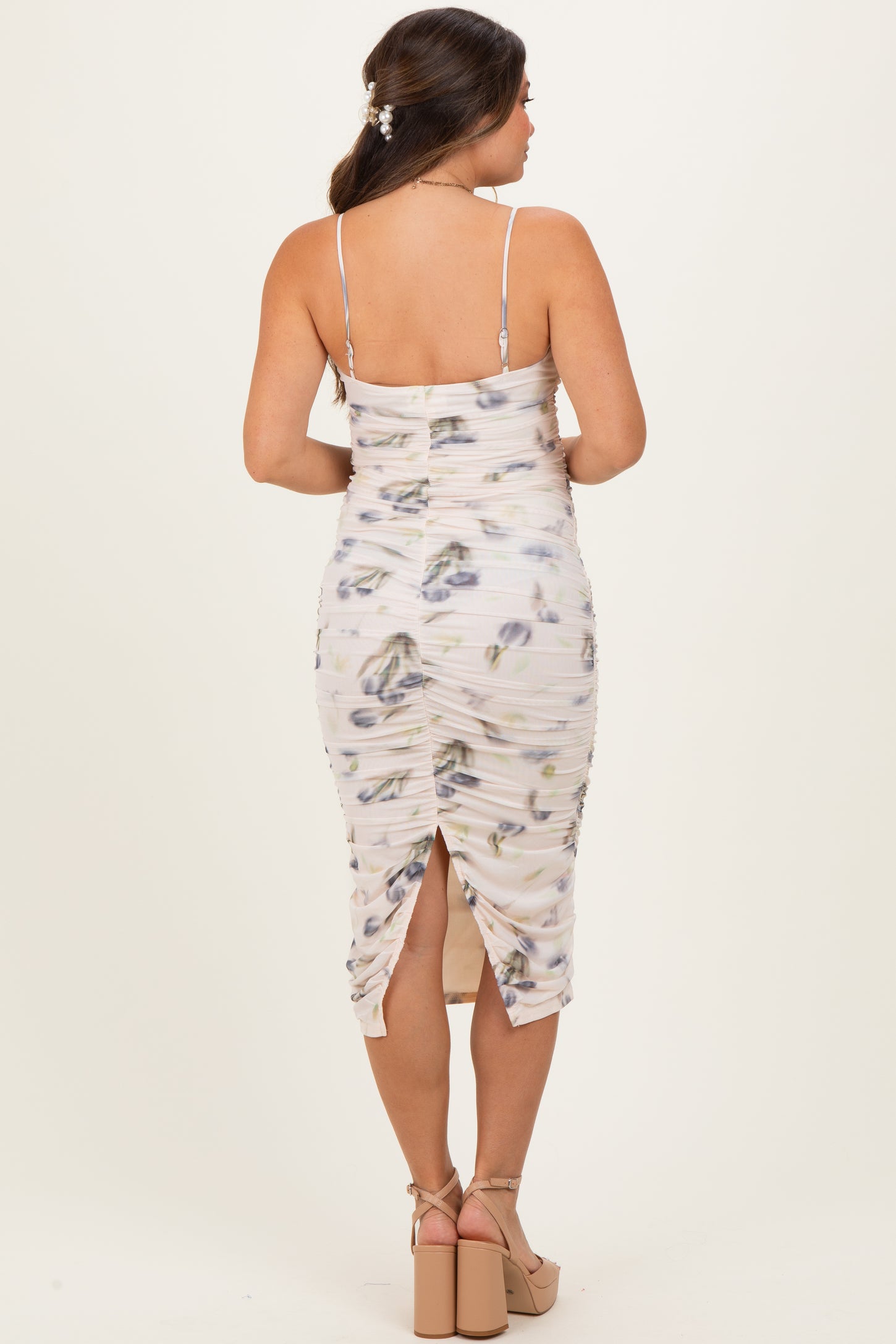 woman wearing a floral print maternity dress with adjustable straps and a fitted silhouette, showing a side slit