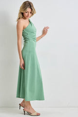 woman wearing a green one-shoulder midi dress with ruched detailing and high heels